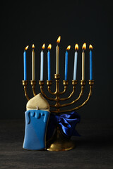 Hanukkiah with ribbon and gingerbread on black background
