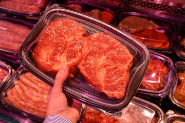 Showcase with meat in box and hand in supermarket,  close up