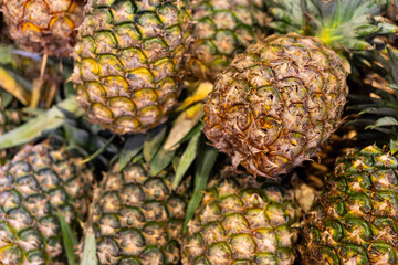 Pineapple background. Pile of ripe pineapples at the market counter. Many yellow fruit stacked at the supermarket. Buying Pineapple at a Grocery Store, Healthy Organic Food.