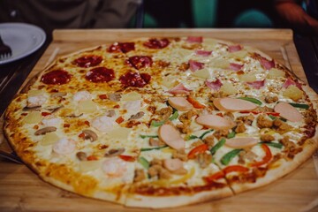 Homemade pizza with tomatoes, mozzarella and ham. Homemade Pizza on a rustic wooden table. Hot pizza slice with melting cheese on a rustic wooden plate.