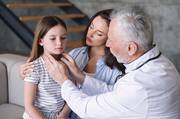 Friendly caring male pediatrician examining kid, touching lymph nodes.
