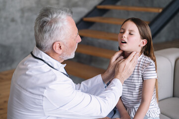 Male pediatrician looking at kids throat through open mouth