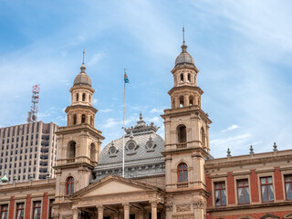 Fototapeta na wymiar South African flag flies atop Palace of Justice, above columned balcony, between domed towers