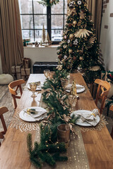 Cozy flat apartment photo studio room green Christmas Tree gifts presents garlands, candles decorated dinner table settings toys balls interior New Year lights glowing bokeh