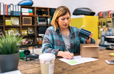 Woman entrepreneur checking return form of wrong package sent to client in online shop. Return...