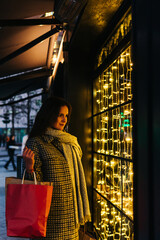 Elegant woman looking at a shopping window with Christmas lights