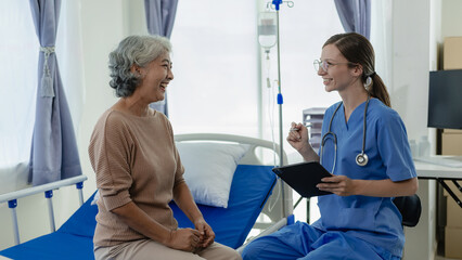 Female doctor with clipboard talking with elderly female patient at hospital Senior woman or doctor...