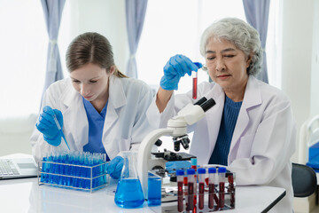 Laboratory, old female doctor and woman doing medical research with blood in tube, beautiful young...