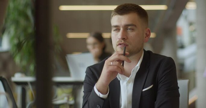 A suited director in a business office employs a pen to contemplate new business ventures, exemplifying strategic thinking and decision-making in the corporate world