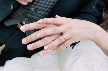 The bride's hand resting on top of the groom's hand, with the wedding rings