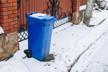 Close up view trash can covered with snow recycling containers with rubbish in front of gate...