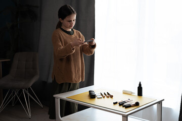 Teenager photographer shooting beauty products on the table at home near the window