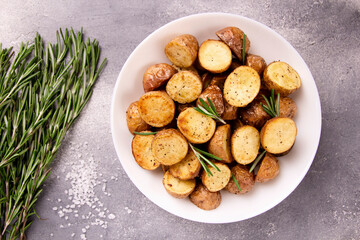 Delicious baked potatoes with rosemary on a gray background