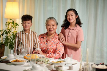 Portrait of cheerful senior Vietnamese woman and her two grandchildren