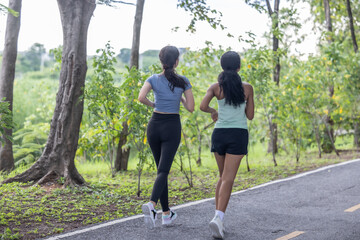 Stylish female runners in modern attire, discover serenity. Reenergize amid jogging the parkway.