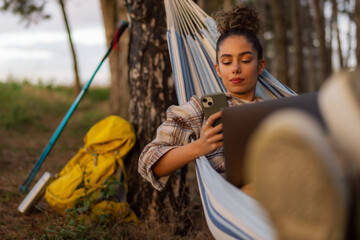 The hiker girl maximizes productivity from her hammock, effortlessly juggling tasks on her laptop...