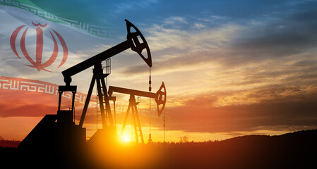 Oil drilling derricks at desert oilfield with Iran flag.