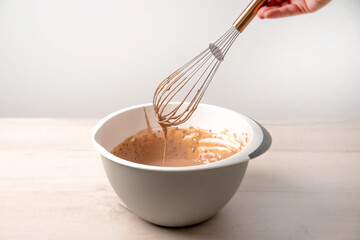 a baking bown with a whisk in a mixture for chocoalte protein pancakes.