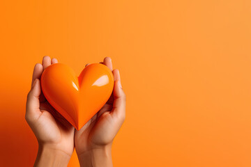 hand holds a heart love shape on an orange background with copy space - obrazy, fototapety, plakaty