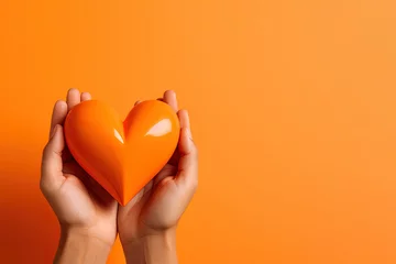 Foto op Canvas hand holds a heart love shape on an orange background with copy space © dewaai
