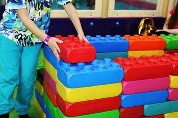 the child's hands build a wall of toy building blocks of different colors
