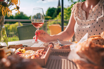 a women holding a glass of rose wine by a table full of tasty food