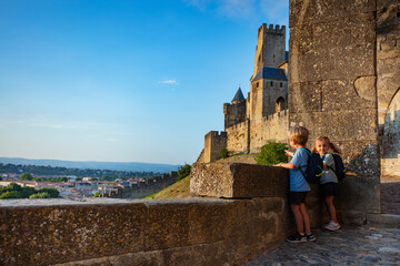 Small backpackers admire Carcassonne castle at summer sunset