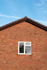 Pitched roof with single window and blue sky