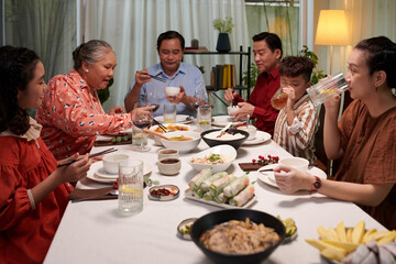 Big family enjoying dishes of Vietnamese cuisine at dinner party - obrazy, fototapety, plakaty