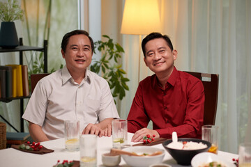 Cheerful mature Vietnamese men attending family dinner