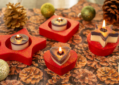 Herz-Teelichthalter mit brennenden Teelicht in rot mit Glitzerstaub. Die Kerzen sind zweifarbig mit Glitzer.