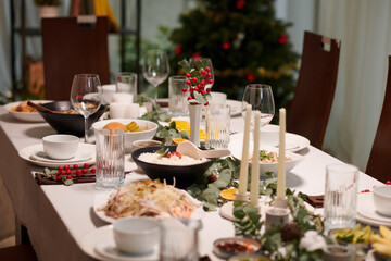 Table served for New Year celebration and decorated with candles and greenery