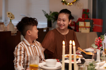 Smiling mother and son sitting at Christmas dinner table