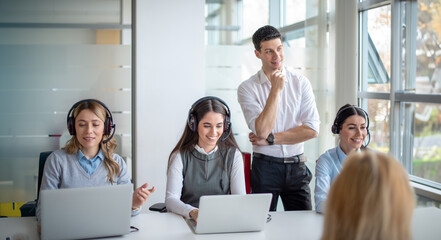 Employees receiving training and guidance in the office call center, where they working with mentor...