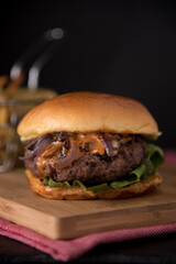 Juicy Homemade burger with lettuce onions, and chipotle sauce in a brioche bun. Dark and moody background.