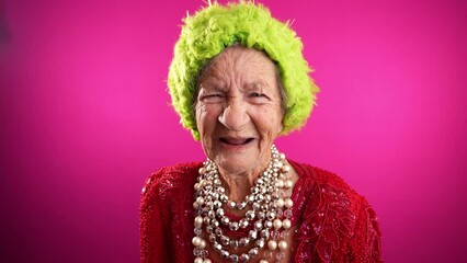 Displeased unhappy fisheye portrait caricature of funny elderly woman saying NO with green hat isolated on pink background.