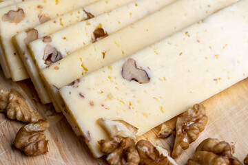 Sliced piece of milk cheese with walnuts