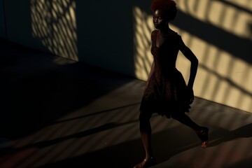 Moving along the city sidewalks, a black woman's path is illuminated by crafted shadows cast by the setting sun