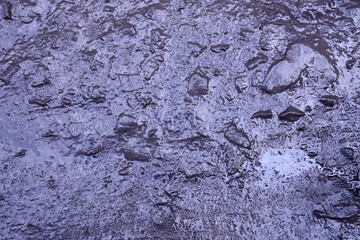 Close up of muddy puddle with small stones on wet surface. Background texture