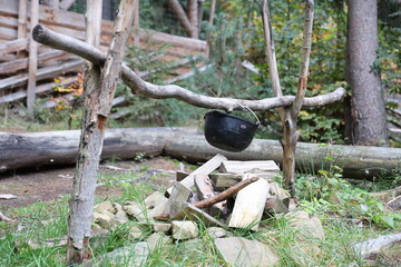 Tourist pot hanging over the fire on a tripod. Cooking in the campaign close up