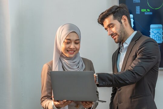Asian muslim woman assistant secretary discussion examining in inspection check data in tablet notebook with boss manager. Boss and muslim woman partnership talking check successful data in laptop.