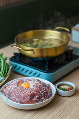 Shabu Shabu or Sukiyaki, a popular dish of pork, beef, and fresh vegetables. Placed on a table with a boiling pot boiling.