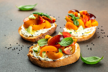 Toast, snack, bruschetta, sandwich with cream cheese, peaches, tomatoes and green basil leaves, Concept healthy and balanced eating. place for text, top view