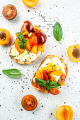 Toast, snack, bruschetta, sandwich with cream cheese, peaches, tomatoes and green basil leaves, Concept healthy and balanced eating. place for text, top view