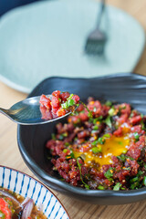 eating Spicy raw beef salad with minced meat and raw eggs on top