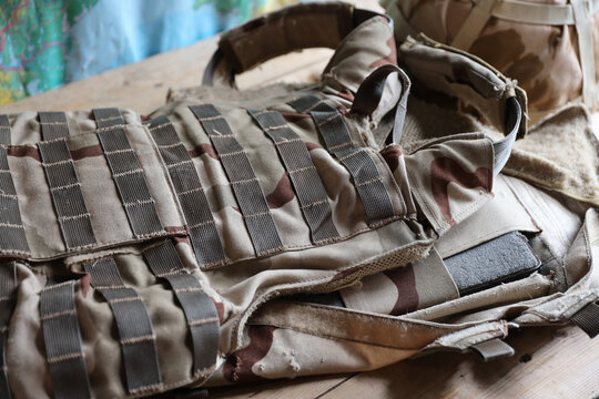 A military helmet of a Ukrainian soldier with a heavy bulletproof vest on wooden table in checkpoint dugout interior
