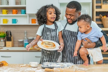 african afro black daughter kids with daddy father happy family funny for teach cooking. Black african daughter afro hair and son enjoy with dad carry hold them preparing dough, bake in the kitchen - obrazy, fototapety, plakaty
