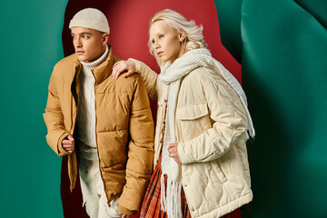 stylish man in beanie and puffer jacket posing with blonde woman on red with turquoise backdrop