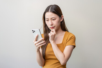 Asian woman reading news in mobile app and wondering fake news.