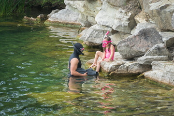 A father teaches his little daughter to snorkel on a lake in the summer.